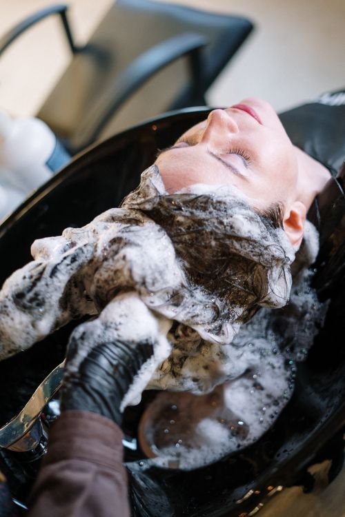 Hair colorist applying balayage highlights with foils in salon