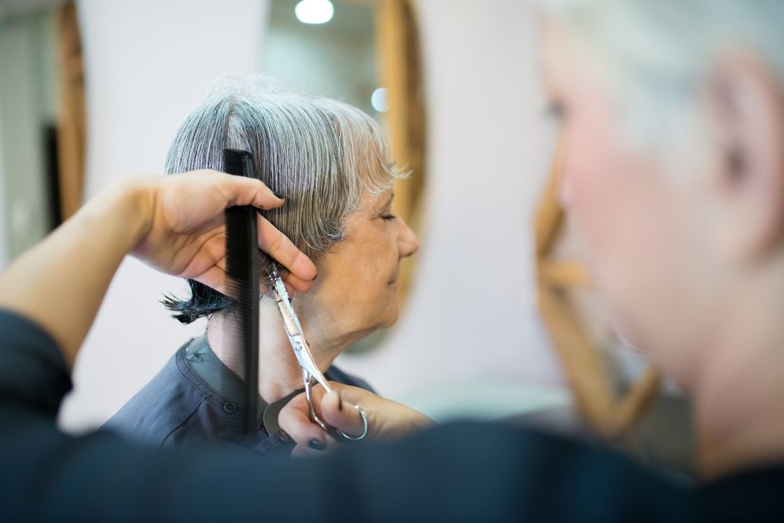 Elderly woman receiving haircut in stylish salon setting