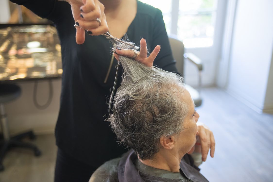 Senior woman getting gray hair styled at salon