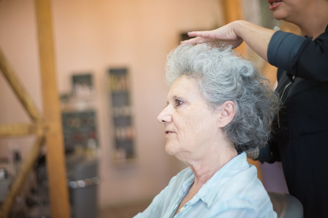 Senior woman getting gray root coverage touch-up at professional salon