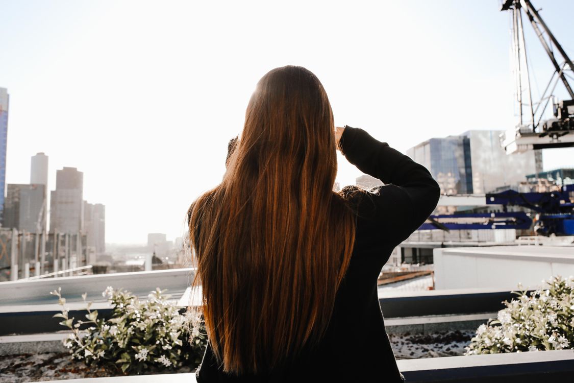 Woman with long, shiny, glossy brown hair after professional gloss treatment