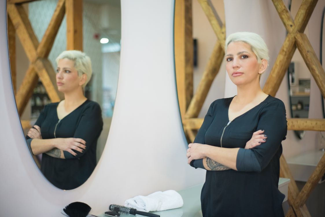 Confident independent hairstylist standing in a modern salon booth rental space