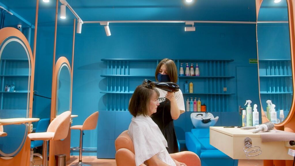 Independent hairstylist styling a client at their rented salon booth