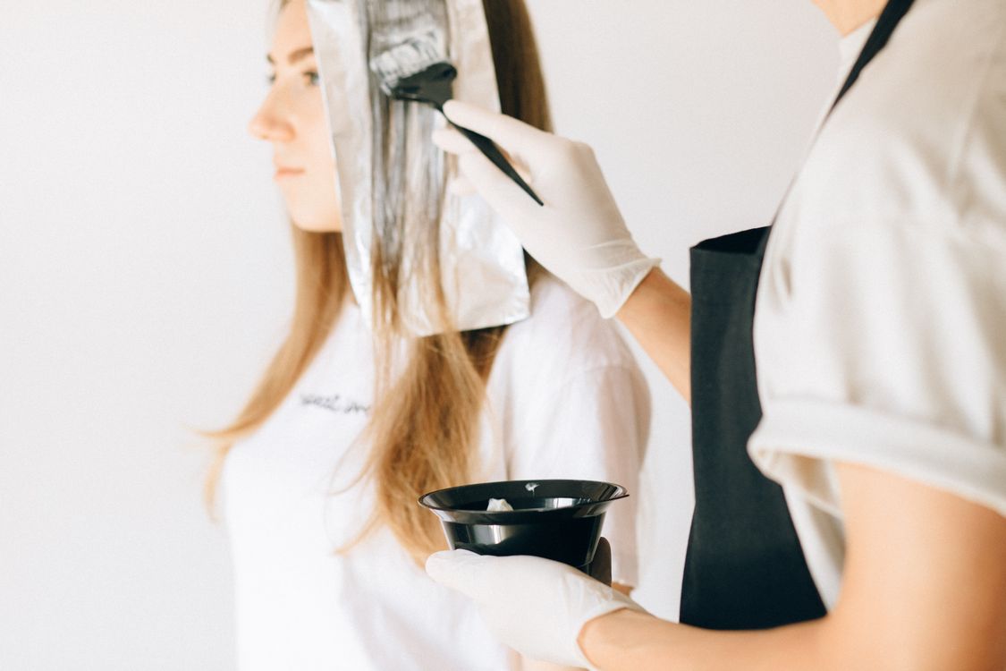 Hairdresser applying fresh hair color with brush to prevent fading