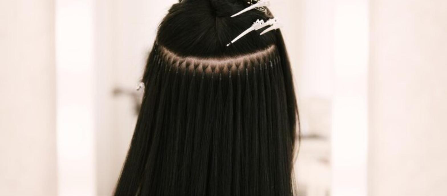 Stylist applying individual hair extension strands to a client at Salon Alure