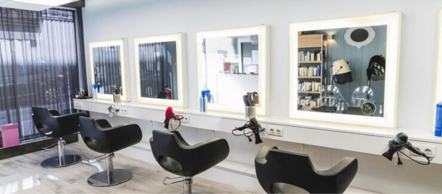 Bright, modern hair salon styling stations with lighted mirrors