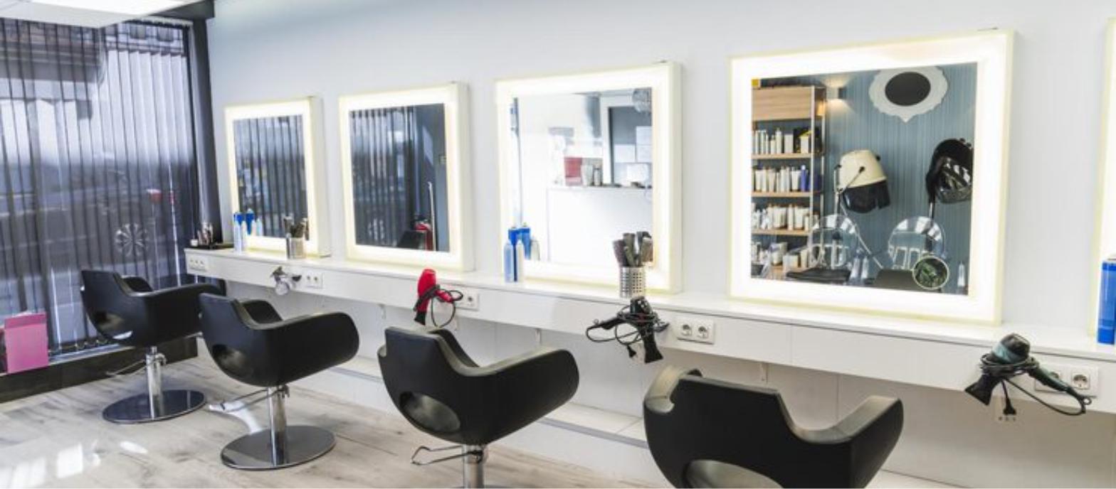 Bright, modern hair salon styling stations with lighted mirrors
